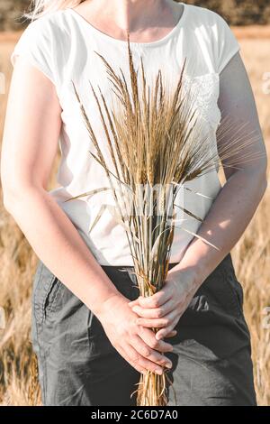 Frau hält Bouquet mit Weizenspikelets in den Händen. Cottagecore Ästhetik. Langsames Leben Stockfoto