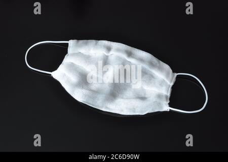 Gaze Bandagen mit elastischen Bändern über den Ohren, zu Hause gemacht, auf schwarzem Hintergrund. COVID-19. Stockfoto