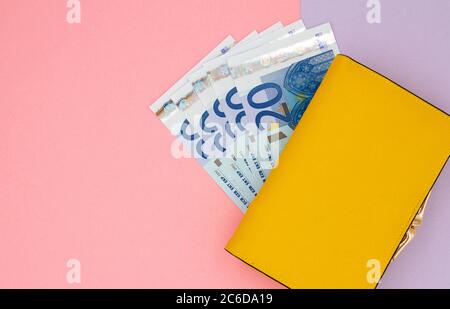 Nahaufnahme der gelben Brieftasche mit 20 Euro-Banknoten auf farbigem Hintergrund Stockfoto