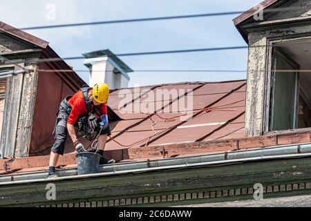 Riga, Lettland - 3. Juli 2020: Industriekletterer entfernt Blätter und Schmutz von der Dachrinne des Hauses Stockfoto