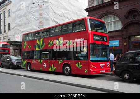 Ein BYD all Electric powered Bus von Metroline betrieben passiert die ursprüngliche Fassade des Oxford Circus Station Stockfoto