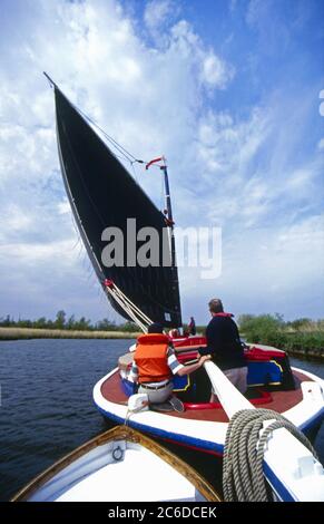 Wherry Albion segelt auf dem Fluss Bure, vom geschleppten Beiboot aus gesehen, Norfolk Broads, England Stockfoto