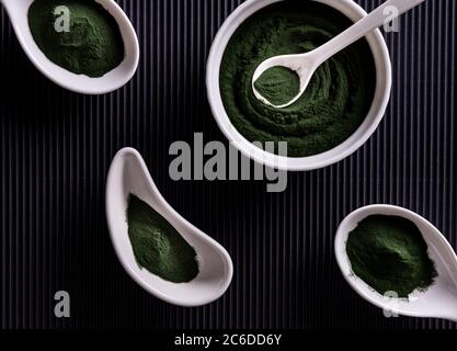 Natürliche grüne Chlorella oder Spirulina Pulver in vier unterschiedlich geformten weißen Porzellanschalen. Gesunde Superfood Ernährung und Diät-Konzept. Stilvolles BL Stockfoto