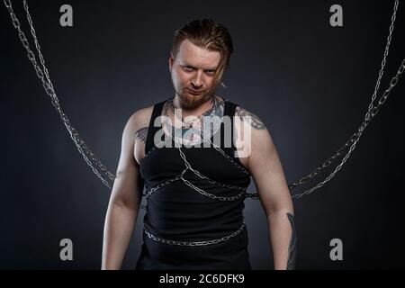 Foto eines tätowierten bärtigen Mannes, der in Ketten gebunden ist Stockfoto