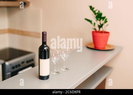 Eine Flasche Wein und zwei leere Gläser an der Bar in der Küche. Stockfoto