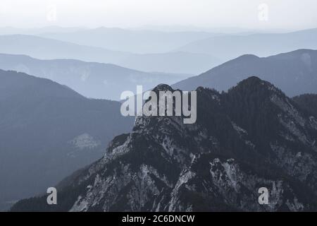 Spektakuläre Aussicht auf graue Bergketten Silhouetten und Nebel in Tälern. Die Julischen Alpen, Nationalpark Triglav, Slowenien. Blick vom Berg Slemenova Stockfoto