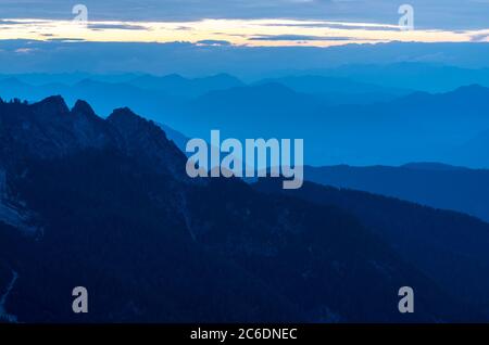 Spektakuläre Aussicht auf blaue Bergketten Silhouetten und Nebel in Tälern. Die Julischen Alpen, Nationalpark Triglav, Slowenien. Blick vom Berg Slemenova Stockfoto