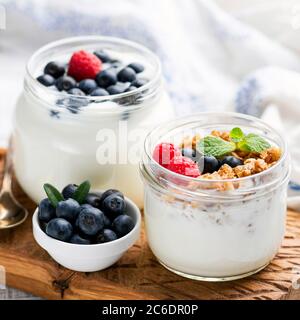 Griechischer Joghurt mit Müsli und Beeren in einem Glas. Gesunder Joghurt-Snack mit knuspriger Haferflocken und Sommerbeeren Stockfoto