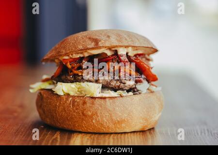 Köstliche frische hausgemachte Käse Burger mit gegrilltem Fleisch, Käse, Tomaten, Salat und Zwiebelringe in Kraftpapier. Stockfoto