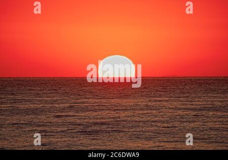Große Sonne über Meer, roter Himmel Stockfoto