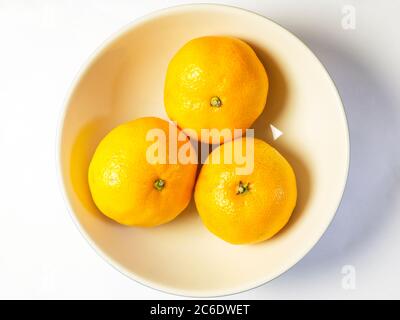 Drei Satsumas in einer Schale isoliert auf weißem Hintergrund Stockfoto