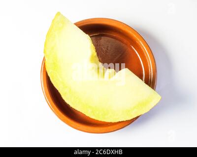 Eine Scheibe frische galia Melone in einer kleinen braunen Schale isoliert auf weißem Hintergrund Stockfoto