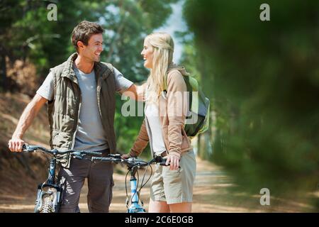 Lächelndes Paar mit Mountainbikes im Wald Stockfoto