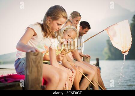 Familie mit Fischernetzen am Dock über dem See Stockfoto