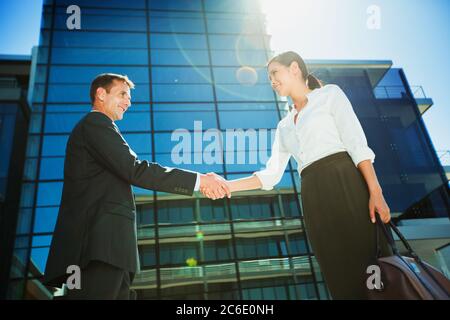 Geschäftsmann und Geschäftsfrau schüttelten sich die Hände unter dem Hochhaus Stockfoto