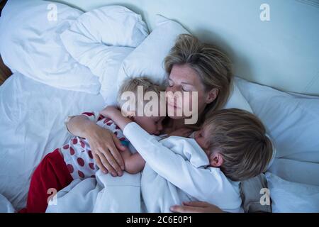 Mutter mit Söhnen, die im Bett schlafen Stockfoto