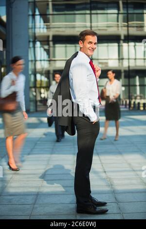 Geschäftsmann, der vor den städtischen Gebäuden lächelt Stockfoto