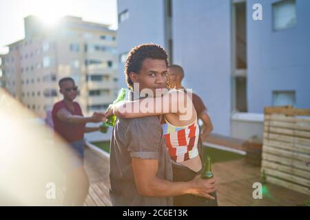 Portrait junges Paar umarmt und trinkt Bier auf dem städtischen Dach Stockfoto