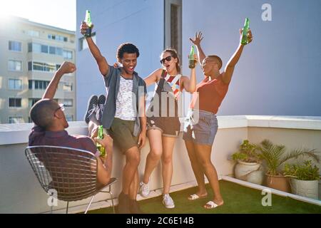 Fröhliche junge Freunde, die auf dem städtischen Dach jubeln und Bier trinken Stockfoto