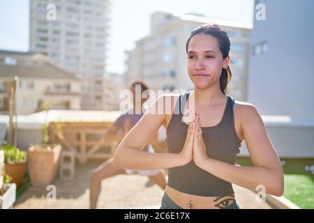 Portrait selbstbewusste junge Frau, die Yoga auf dem sonnigen Dach praktiziert Stockfoto