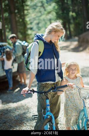 Lächelnde Mutter und Tochter mit Fahrrädern im Wald Stockfoto