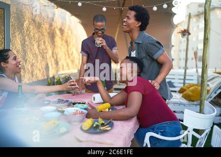 Glückliche junge Freunde mit Smartphone essen Mittagessen auf der Terrasse Tisch Stockfoto