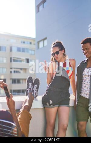 Coole junge Frau gestikuliert Frieden Zeichen auf sonnigen städtischen Dach Stockfoto