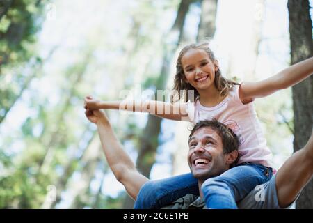 Vater, der die Tochter auf den Schultern in den Wäldern trägt Stockfoto