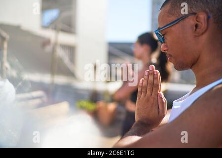 Ruhiger junger Mann, der Yoga auf der sonnigen Terrasse praktiziert Stockfoto