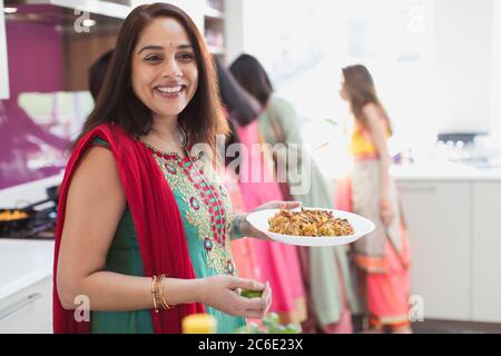 Portrait glücklich indisch Frau in sari Essen in der Küche Stockfoto