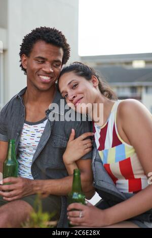 Glückliche junge Freunde trinken Bier auf der Terrasse Stockfoto