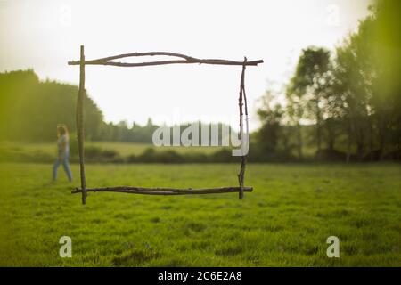 Ast Rahmen über Frau zu Fuß in idyllischem Grasfeld Stockfoto