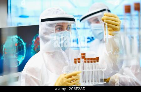 Wissenschaftler in Reinanzügen, die Coronavirus-Impfstoff erforschen Stockfoto