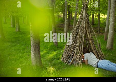 Frau, die sich im Ast-Tipi im Wald entspannt Stockfoto