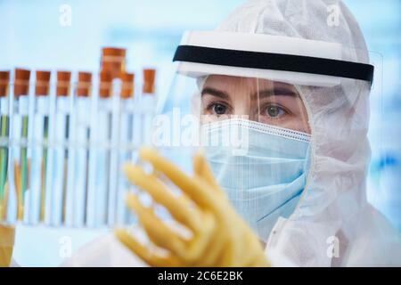 Wissenschaftlerin im Reinanzug, die Reagenzgläser untersucht Stockfoto