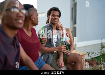 Portrait selbstbewusster junger Mann, der mit Freunden auf der Terrasse Bier trinkt Stockfoto