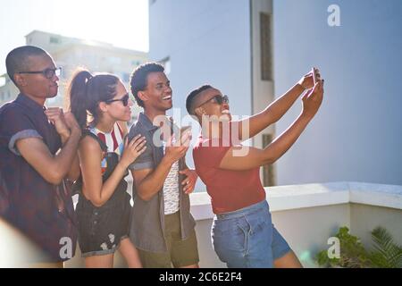 Glückliche junge Freunde, die Selfie auf einem sonnigen städtischen Balkon machen Stockfoto