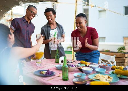 Glückliche junge Freunde essen Mittagessen auf der Terrasse Tisch Stockfoto