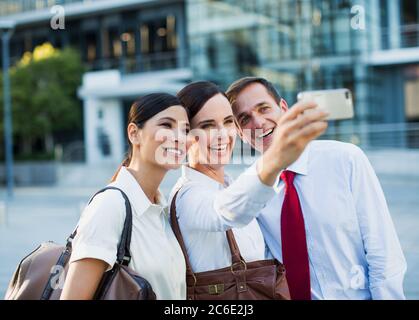 Lächelnde Geschäftsleute, die im Freien Selbstporträts machen Stockfoto