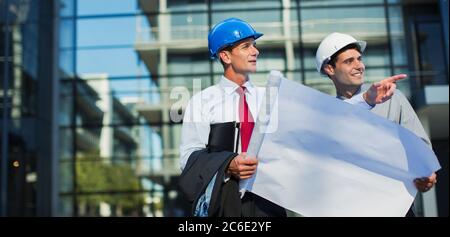 Architekten mit Plänen außerhalb des Stadtgebäudes Stockfoto
