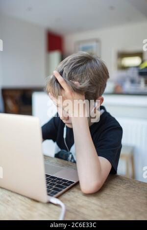 Junge mit Kopfhörer Heimschooling am Laptop Stockfoto