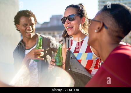 Fröhliche junge Freunde trinken Bier auf sonnigem Balkon Stockfoto
