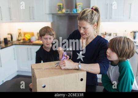 Mutter und Söhne öffnen Paket in der Küche Stockfoto