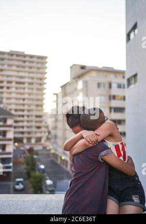 Glückliches junges Paar umarmt auf städtischen Balkon Stockfoto