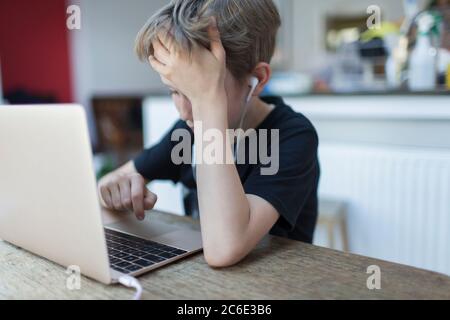 Frustrierter Junge mit Kopfhörern Heimschooling am Laptop Stockfoto