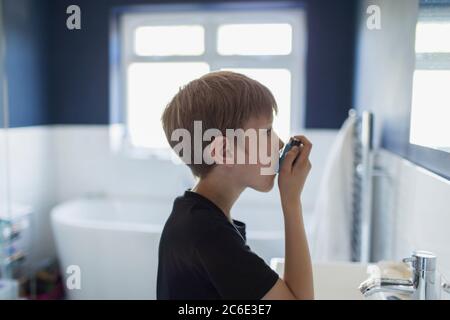 Junge mit Asthma mit Inhalator im Badezimmer Stockfoto
