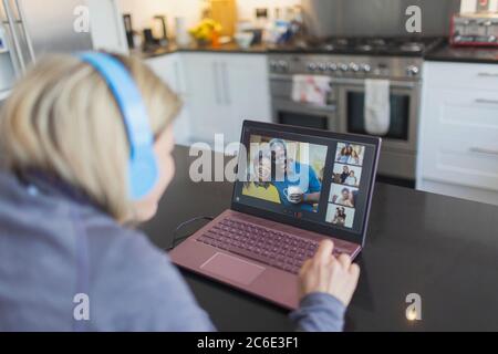 Frau mit Kopfhörer und Laptop Video chatten mit Freunden Stockfoto