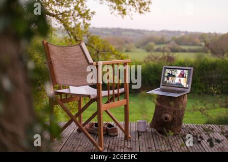 Kollegen chatten auf dem Laptop-Bildschirm auf dem ländlichen Balkon Stockfoto