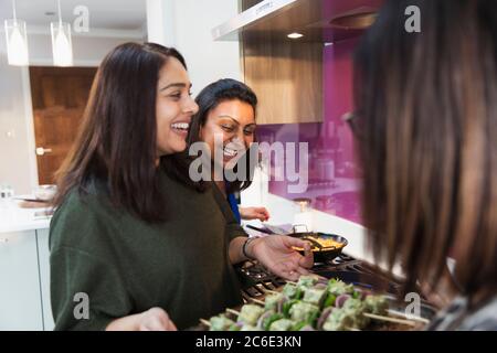 Glückliche indische Frauen, die in der Küche Essen zubereiten Stockfoto