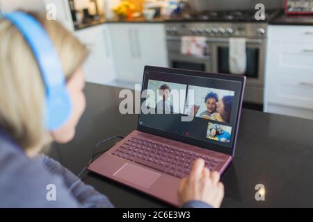 Frau mit Kopfhörer und Laptop Video chatten mit Freunden Stockfoto